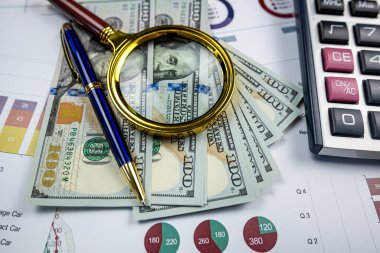 business graphs paper with dollar bills magnifying glass calculator and pen on office desk. Growth charts, Stock exchange trading