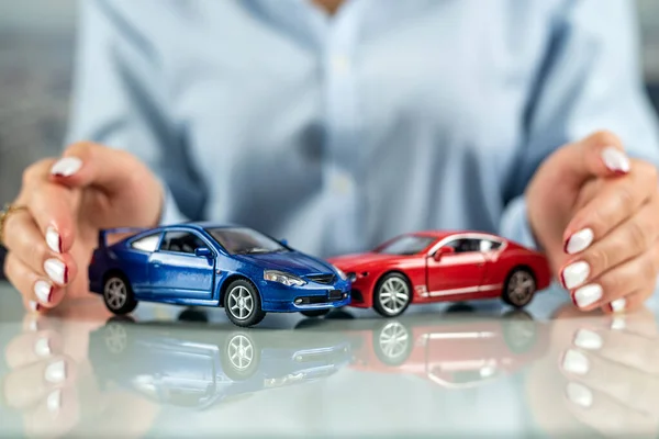 Insurance agent woman simulating an accident with two mini cars on the table. The concept of a car accident. life and health insurance in case of an accident