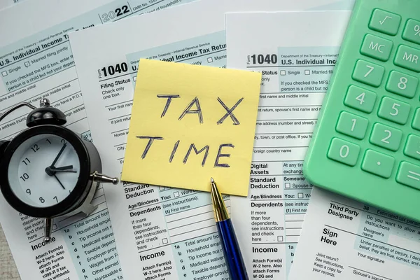 yellow sticker with world Tax Time on 1040 tax form, Tax concept deadline