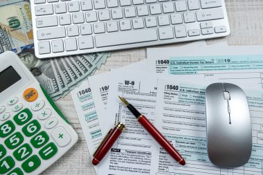 business accounting concept - 1040 tax form with pen calculator us dollar bills. Deadline