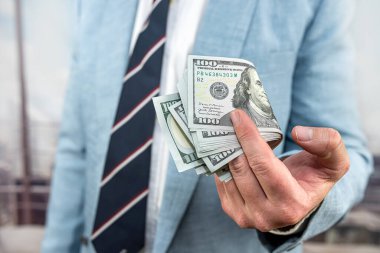 Man's hand showing 100 dollar bills. Businessman counts money. Finance concept