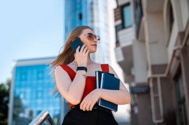 Markalı elbiseli esmer bir kadın akıllı telefon uygulaması üzerinden taksi çağırır. Güçlü kadın kavramı.