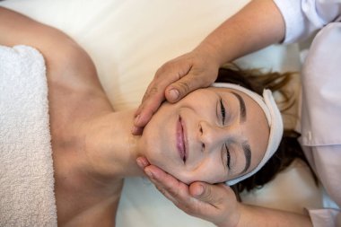 strong female masseur is doing a cosmetology facial massage to a client. spa salon concept. facial skin tightening
