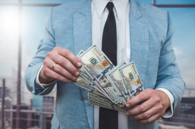 closeup businessman in suit holding one hundred 100 dollar bill. money concept
