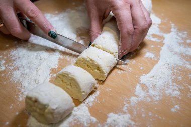 Female hands cut with knife raw sweet dough, the process of making cheesecakes. Cooking food 