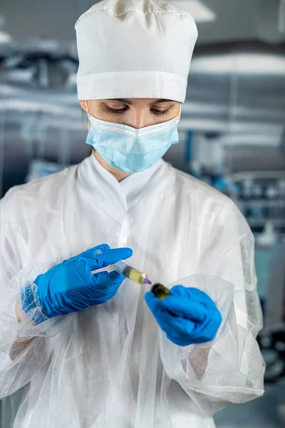 female doctor or assistant wearing blue uniform holding syringe with medicine in surgery room. operating room medical personnel clinic staff. syringe