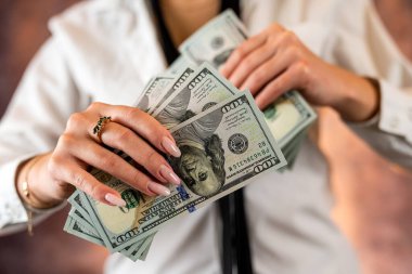 Cropped photo of a woman holding US dollar money in her hands on the background of her body. isolated on plain background. budget planning. the concept of profit