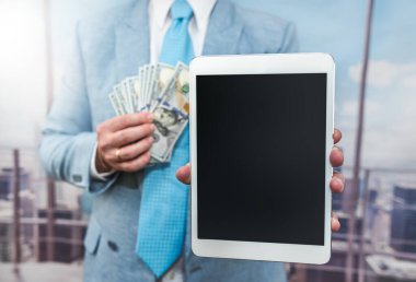 businessman in suit hold dollar and tablet at office, online purchase concept