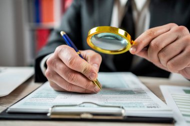 İş adamı ofisinde büyüteç kullanarak 1040 boş vergi formuna bakıyor. Muhasebe kavramı, vergi zamanı