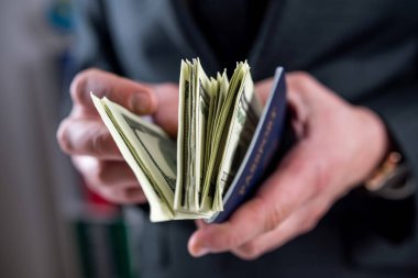 ABD pasaportlu bir adam iş ya da seyahat için dolar ve finans konseptine sahip.