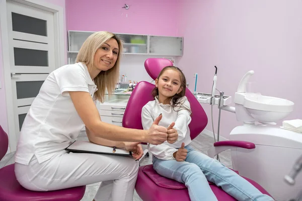 happy female dentist is interviewing a little girl patient in the office of a children\'s dental clinic. Dentistry technology. technology and healthcare concept. children\'s dentistry