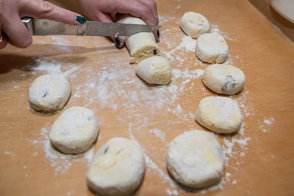 stock image closeup of female hands in flour with a knife cut dough sausage in small pieces on a wooden board. Ukraine tasty traditional food