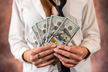 Cropped photo of a woman holding US dollar money in her hands on the background of her body. isolated on plain background. budget planning. the concept of profit
