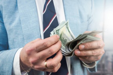 Man's hand showing 100 dollar bills. Businessman counts money. Finance concept