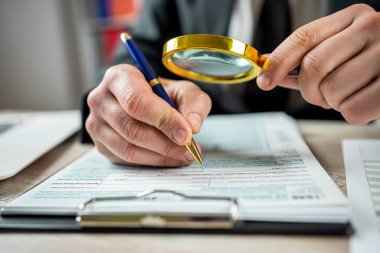 Male hand using magnifying glass and work with 1040 tax form, legal business contract. Accounting concept