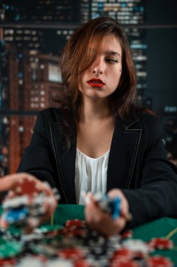 girl as a poker player with a lot of colored chips at a round green table. casino poker concept woman. big win