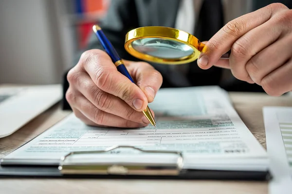 stock image Male hand using magnifying glass and work with 1040 tax form, legal business contract. Accounting concept