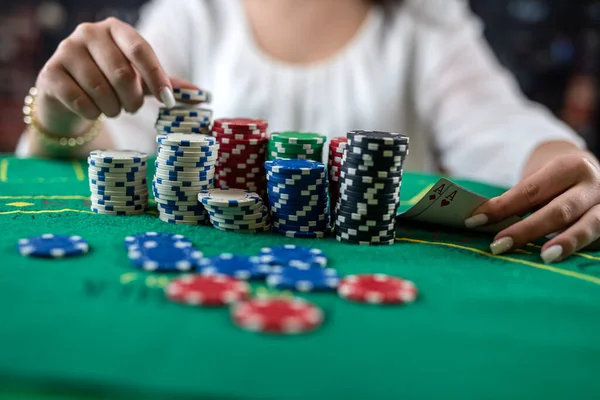 female hands pick up poker chips from a pile at a round poker table. risky bets in poker. woman in casino. the woman won the game