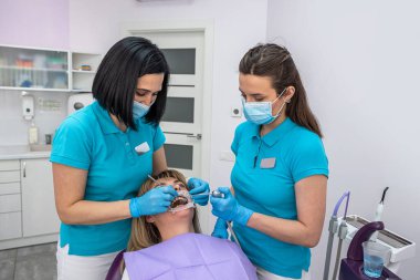 female dentist shows a girl trainee how to properly examine the oral cavity. Dentist and trainee concept