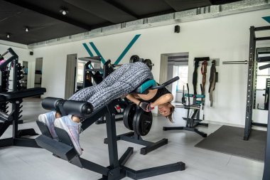 Çekici esmer kız spor salonunda halterle egzersiz yapıyor. Ağırlık kaldırma, ağırlık kaldırma ve ağırlık kaldırma eğitimi alıyorum. Spor. fitness konsepti.