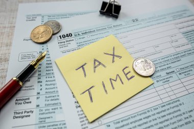sticker with text TAX TIME with 2022 blank 1040 tax form. Deadline, paperwork