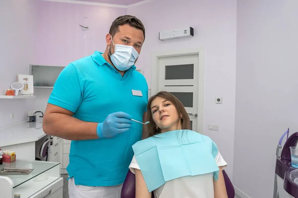 the chief dentist examines the treated healed teeth in a young woman. The concept of preventive examination in dentistry