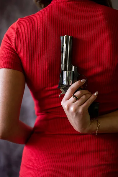closeup spy woman wear red dress holding black gandgun at the grey background
