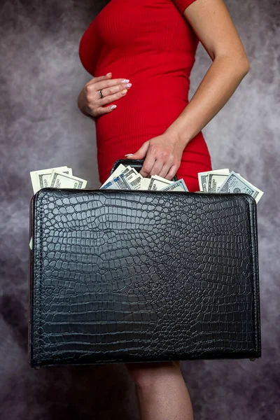 年轻女子身穿红色连衣裙 头戴黑色公文包 装着美元钞票 商业和金融概念 — 图库照片