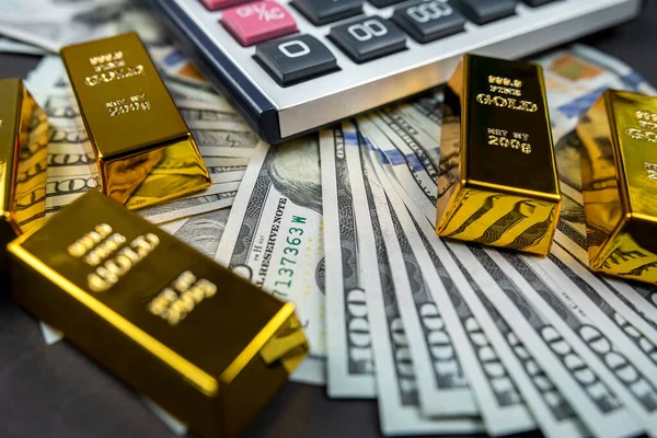 gold bars lie with a calculator near a large sum of dollars isolated. Concept of financial savings. gold and dollars.