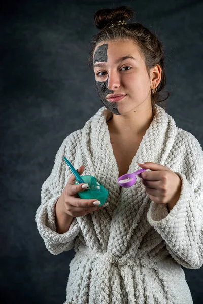 Fiatal Lány Fehér Fürdőköpenyben Alkalmazása Resztoratív Fekete Maszk Arcon Ecsettel — Stock Fotó