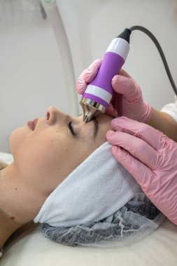 Güzellik uzmanı, kaplıcadaki kadın yüzünde fonoforez donanım ile temizlik prosedürü yapıyor. Gençleştirme prosedürü, cilt bakımı. 