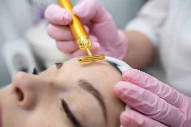 Kaplıcadaki genç bir kadın, yüz masajıyla, gençleştirme prosedürünü sıkılaştırıyor. Kadın vücut bakımı