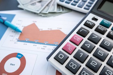 Ofis masasında kalem ve hesap makinesiyle iş dengesi raporu. Birçok grafik ve grafik