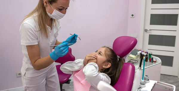 little patient covers her mouth with her hands and does not allow the dentist to look into her mouth. fear of the dentist. the child is afraid dentistry
