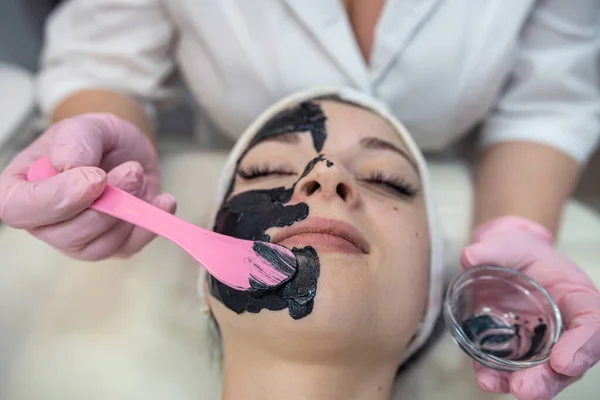 Estetista Applicare Maschera Nera Giovane Bella Faccia Donna Nel Salone — Foto Stock