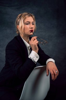 Stüdyoda izole edilmiş kadın portresi zarif, zarif, siyah takım elbiseli, sandalyede oturan moda kadını modeli. izole etme