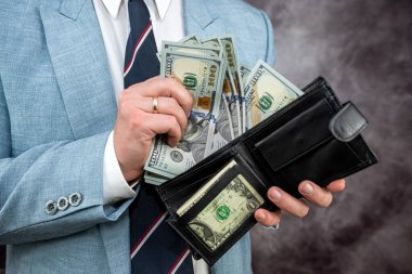business man accounting or gets money in the wallet purse full of dollars, finance or shopping concept