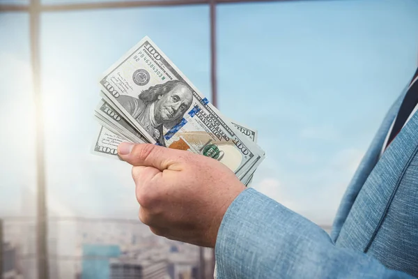 stock image closeup businessman in suit holding one hundred 100 dollar bill. money concept