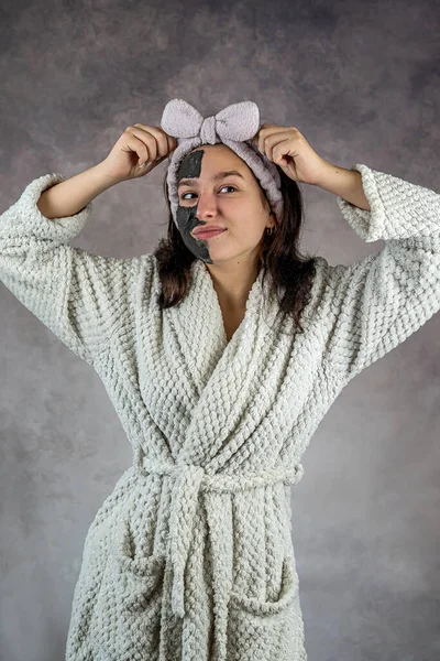Menina Aplicando Rosto Facial Preto Isolado Fundo Cinza Estilo Vida — Fotografia de Stock