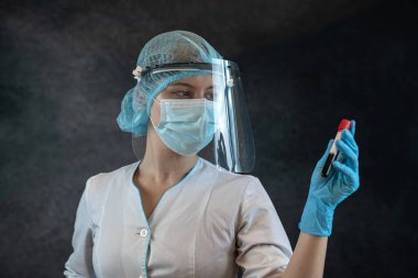 Doktorun elinde deney tüpü şişesi ve koyu arka planda kan örneği var. Klinik laboratuarında örnek oluşturma