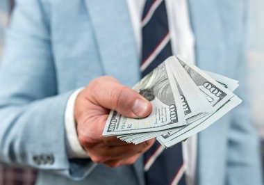 Yakından 100 Amerikan doları banknotlar erkeklerin elinde. Başarılı işadamının elinde para var.