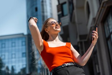 Markalı elbiseli esmer bir kadın akıllı telefon uygulaması üzerinden taksi çağırır. Güçlü kadın kavramı.