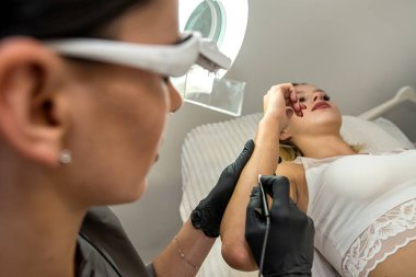 female cosmetologist  use hardware permanent removal of unwanted hand hair in her young woman client at medical cabinet. Concept of beauty and clean skin