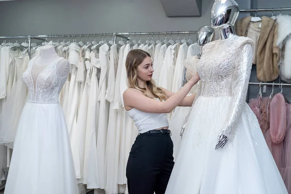 A pretty sales consultant measures a wedding dress for a client and shows impeccable quality. Bridal store