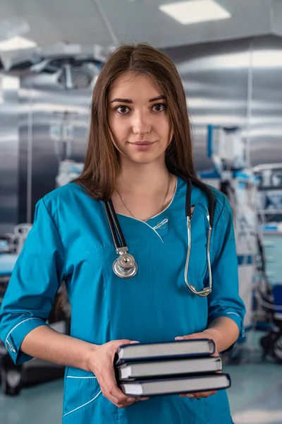 young beautiful doctor woman standing in the operating room with books in her hands. medicine. doctor with books