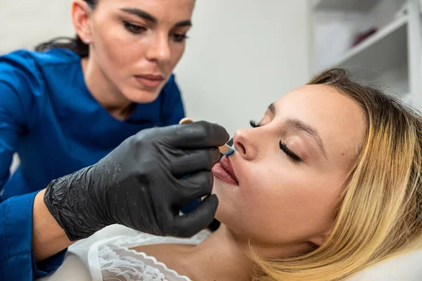 stock image Young woman client get removing hair on the upper lip in face with hot sugar wax a beauty treament procedure in spa clinic. Concept of skin and health care