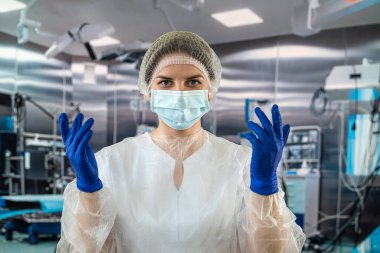 Mavi ceketli doktor ya da hemşire mavi lastik eldiven giyer ve bir hastayı ameliyathanede muayene etmeye hazırlanır. İlaç. Ameliyathane doktorları ve cerrahları.
