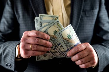 şık takım elbiseli adam birikimlerini dolar banknotlarıyla sayıyor. Eller dolar sayıyor. Takım elbiseli bir adam.