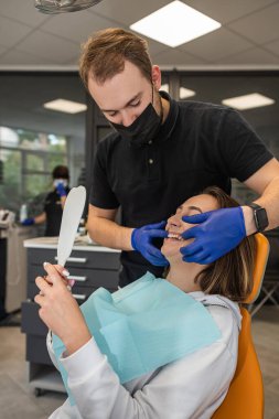 Dişçi dişlerini tedavi etmeye gelen hastayı ayrıntılı bir şekilde muayene eder. diş hekimliği