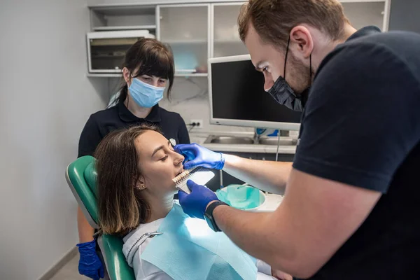 In professional practice, the dentist checks the level of whitening of the patient's teeth by staining them from the doctor. Concept: dentists. health care. perfection. white.